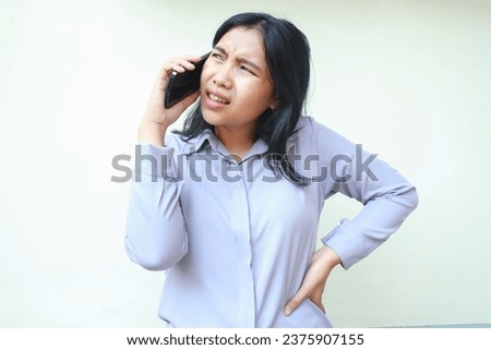 confused asian young woman puzzled having conversation on cellphone looking away with hand on waist, isolated on white female thinking suspicious dressed in formal suit