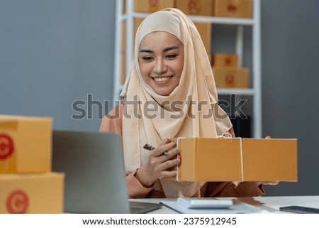 Small business startup entrepreneur or Muslim woman, Islamic freelancer using laptop working with parcel boxes, packaging, online marketing and shipping. Startup business ideas, SME