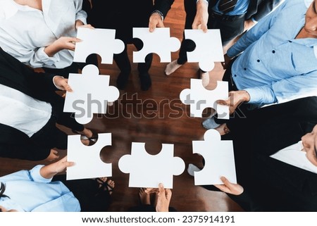 Top view multiethnic business people holding jigsaw pieces and merge them together as effective solution solving teamwork, shared vision and common goal combining diverse talent. Meticulous Royalty-Free Stock Photo #2375914191