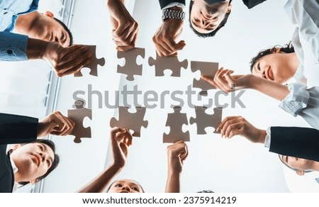 Multiethnic business people holding jigsaw pieces and merge them together as effective solution solving teamwork, shared vision and common goal combining diverse talent. Below view. Habiliment Royalty-Free Stock Photo #2375914219
