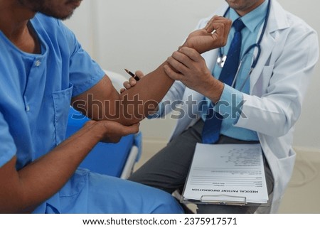 A male doctor is holding his wrist to measure his heartbeat. Pain in the arm muscles of male patients for diagnosis and treatment planning. Providing disease control drugs medical service concept.