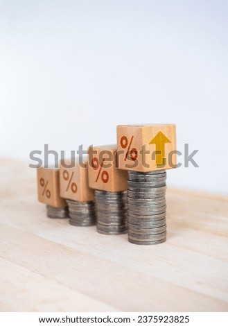 Percentage icon and up arrow on wooden cube blocks on coin stacked bar graph chart steps on white background. Investment, profit, develop income, sales, business growth, economic improvement concepts.