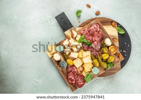 Appetizers table with different antipasti salami, cheese and olives on a light background top view. place for text. Royalty-Free Stock Photo #2375947841