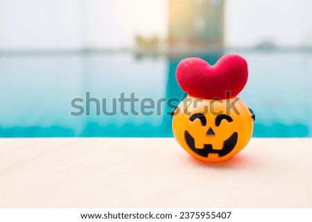 Red heart in Halloween pumpkin on swimming pool edge, outdoor day light, Happy Halloween background idea