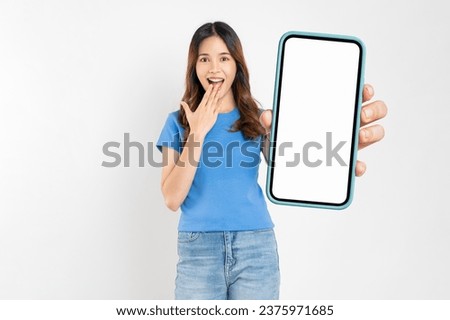 Beautiful Asian woman holding smartphone mockup of blank screen and shows hand sign on white background.