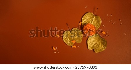 Beautiful golden leaves or 'Sonapatta' placed with Marigold flower on bright red background. Dussehra Greeting card cover with plenty of clear space for text. Royalty-Free Stock Photo #2375978893