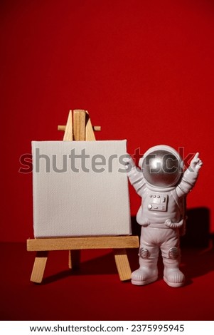 Plastic toy astronaut with paper note template mock up for your text on colorful red background Copy space. Concept of out of earth travel, private spaceman commercial flights missions and Royalty-Free Stock Photo #2375995945