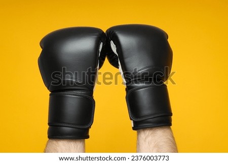 Black boxing gloves on a yellow background