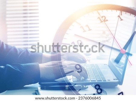 Working hours and working overtime. Close-up view of an employee typing on a computer with a clock overlapping. concept of effective time management and scheduling of company work hours. Royalty-Free Stock Photo #2376006845