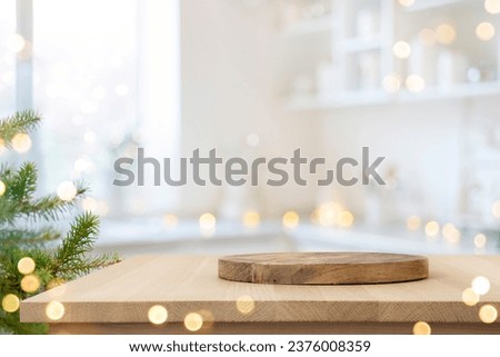 Dish serving or cutting board on wooden table in blurred kitchen with Christmas tree
