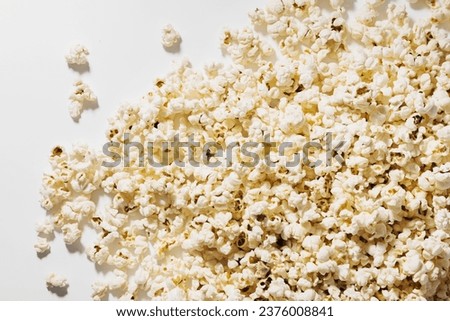 Scattered popcorn on white background with hard lighting.