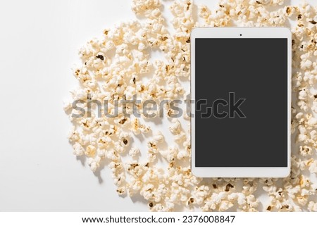 Scattered delicious popcorn and tablet computer with blank screen for your design