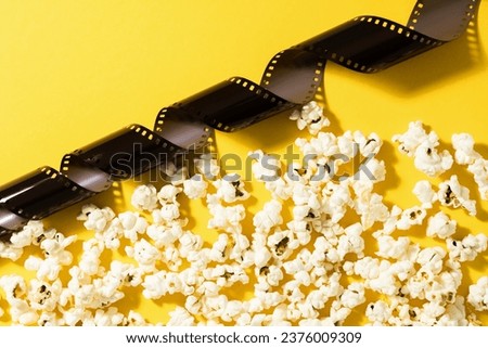 Film stock and popcorn on yellow background