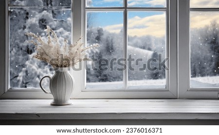 A delicate vase adorns a tall white window, resting on a white wooden table. A framed picture of a snowy landscape serves as the background Royalty-Free Stock Photo #2376016371
