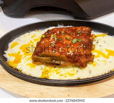 a dish of pork with cheese and sauce.