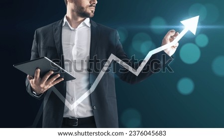 Close up of businessman with tablet pointing at creative glowing upward arrow on blurry glowing blue bokeh circles background. Growth, success business and up concept. Toned image