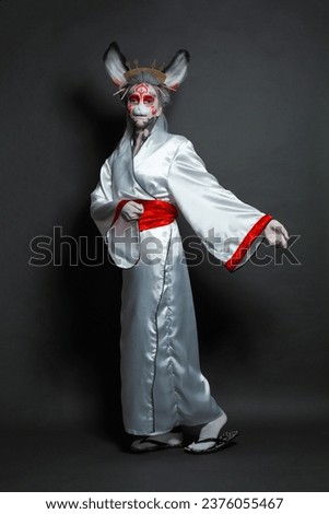 Perfect young woman wearing animal mask and white kimono standing on black background, full length portrait. Halloween, Carnival and Cosplay concept