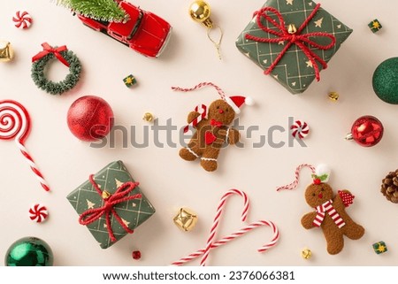 Whimsical New Year's Setup. Top-view shot of gifts sporting rustic bows, mingled with balls, gingerbread man figurines, bells, candies, etc on neutral backdrop. Perfect for greetings or promotions Royalty-Free Stock Photo #2376066381