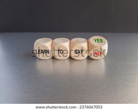 Turned a cube and changes the expression learn to say yes to learn to say no. Beautiful grey table black background. Copy space. Royalty-Free Stock Photo #2376067053