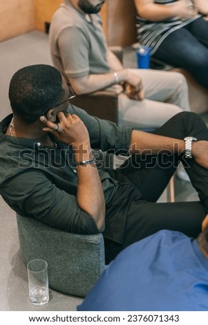 Well-dressed african-american man sitting and talking with another person while attending a meeting
