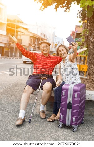Senior Chinese tourist with his friend European poses happy and take a photo selfie on sun flare and blurred of city background.