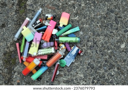 A collection of discarded electronic cigarette vapes have been collected and placed together over a worn concrete floor Royalty-Free Stock Photo #2376079793