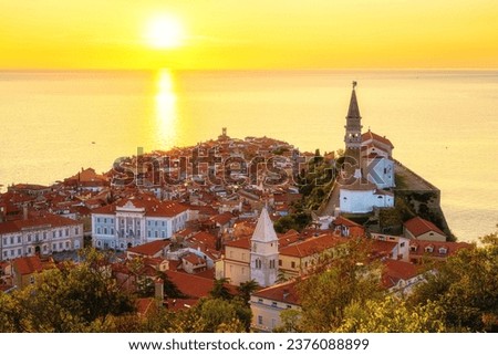 Piran Old Town, Slovenia, scenic cityscape. Top view of medieval architecture with church of St. George, Adriatic Sea and sky in sunset light from Old City Walls, outdoor travel background