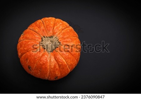 One ripe beautiful orange autumn pumpkin on black background. Сoncept Halloween celebration background, fall harvest, minimalism holiday decoration template. Top view, flat lay, copy space 