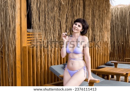 Beautiful brunette woman relaxing in Cabana beach house, personalized luxury vacation resort.