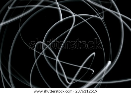 Abstract white lights, grey and blue tones, dark background, abstract shapes, luminous lines in darkness, no people, long exposure photography, moving fine lines 