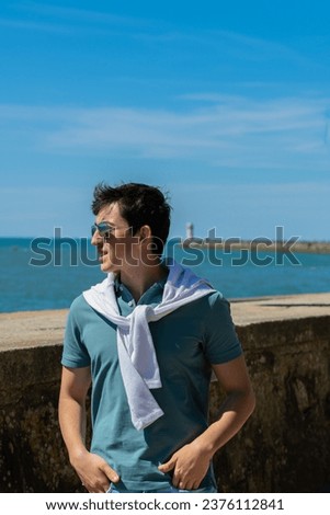 Teenager with sunglasses and white sweater on her neck with the blue sky in the background
