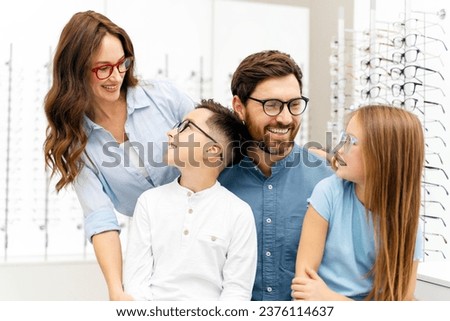 Young beautiful smiling family choosing glasses in modern optical store looking each other. Health care, Vision concept Royalty-Free Stock Photo #2376114637