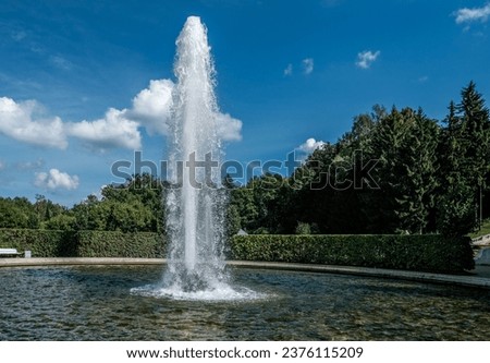 A high jet of water in a fountain in the park on a summer day.