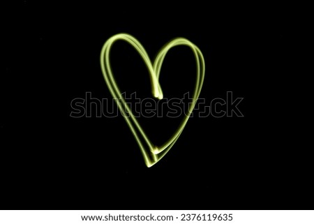 Abstract yellow lights in the shape of a heart, white tones, dark background, shapes in the air, luminous lines in darkness, no people, long exposure photography, moving fine lines