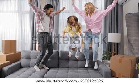 Happy family move into new house. Little girl jump sofa. Crazy child have fun. Funny dad buy flat. Silly kid play home. Joyful mom rest couch. Sale real estate concept. Smiling people rent furniture.