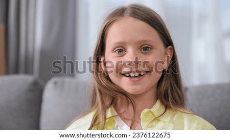 Cute little girl look camera. Happy child portrait close up. Joyful european kid smile. One american face head shot. Nice model have fun. Pupil sit sofa. Blue eyes gaze. Young pretty person posing. Royalty-Free Stock Photo #2376122675