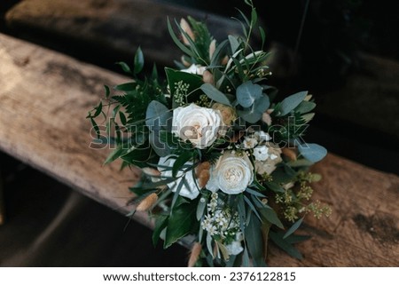 Elegant bridal flower bouquet with white roses laying on a wooden bench Royalty-Free Stock Photo #2376122815