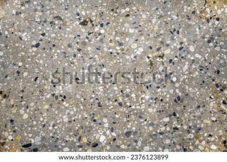 The floor covering is made of cement mortar of small pebbles and pebbles of black and white color or breccia. Construction interior background.