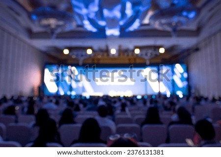 Blurred image of stage with rear view of audience in the conference hall or seminar meeting, business and education about investment concept. Royalty-Free Stock Photo #2376131381
