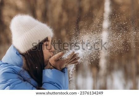 Beautiful young woman blowing snowflakes, selective focus. High quality photo