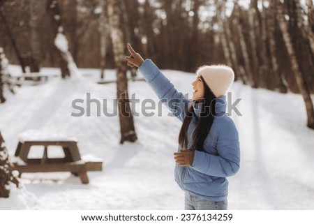 Portrait of a winter woman in warm clothes, Woman breathes on her arms to keep them warm on a cold winter day, Beautiful young woman outdoors. Cold weather concept, frozen hands. High quality photo