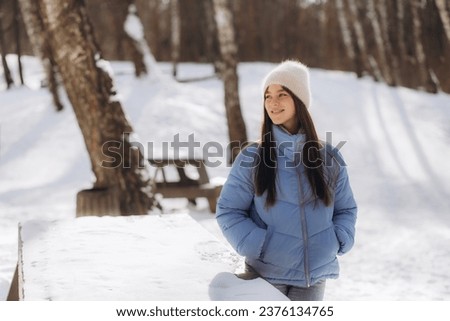Portrait of happy beautiful girl, young joyful positive woman walking playing with snow, snowflakes, having fun outdoors in winter clothes, hat and scarf, smiling. Winter season, weather . 
