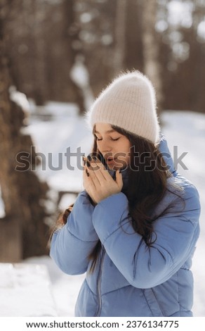 Young girl breathes on her hands to keep warm at cold winter day. Girl warms her hands with a warm breath. High quality photo