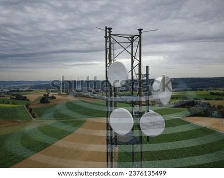Mobile radio tower in the open nature, with fields, forests and meadows. Slightly cloudy, beautifully textured sky. Virtual icons regarding data connections and access to cloud data, phone, email. Royalty-Free Stock Photo #2376135499