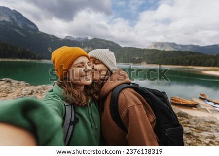 Young cheerful romantic lesbian couple traveling together in the mountains taking selfies  Royalty-Free Stock Photo #2376138319