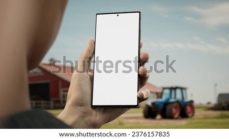 CU Male farmer checking his phone near the farm, blank screen phone mockup