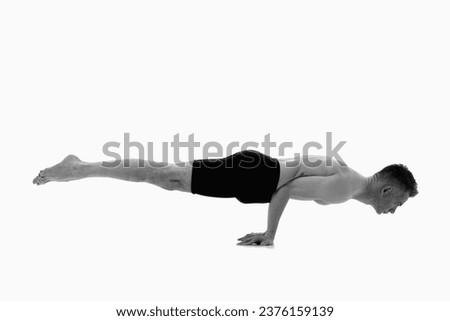 Mayurasana (Peacock Posture), Ashtanga yoga  Side view of man wearing sportswear doing Yoga exercise against white background.  Black and white image.