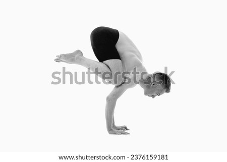 Bakasana ( Crane pose), Ashtanga yoga  Side view of man wearing sportswear doing Yoga exercise against white background. Black and white image.