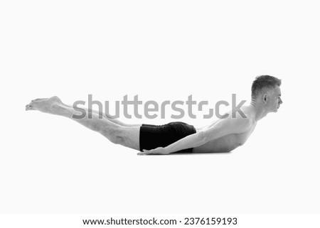 Shalabhasana (LOCUST POSE), Ashtanga yoga  Side view of man wearing sportswear doing Yoga exercise against white background.  Black and white image.