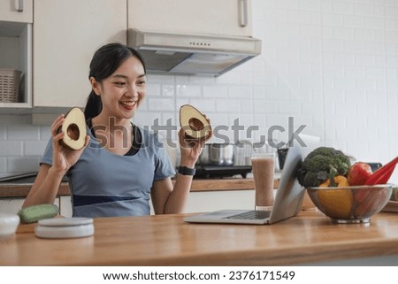 Beautiful Asian woman in workout clothes searches for healthy recipes online on her laptop. while preparing healthy food in the kitchen
